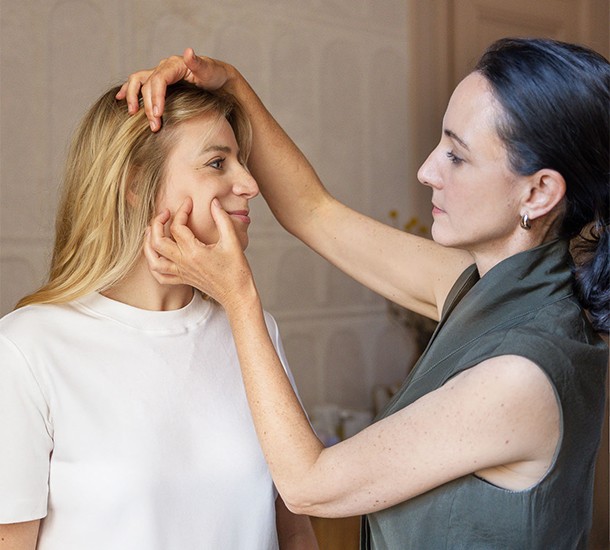 Facialiste réalisant un diagnostic morphofacial sur le visage d'une cliente