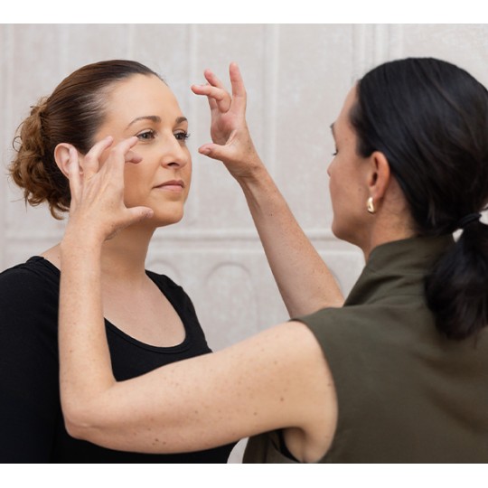 Facialiste réalisant un diagnostic morphofacial sur le visage d'une cliente