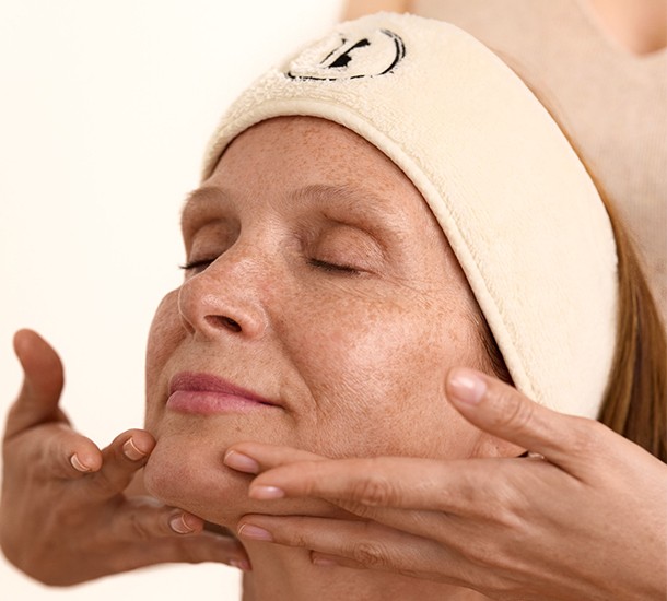 Gestuelle précise des mains sculptant le bas du visage et le menton d'une femme au visage relevé