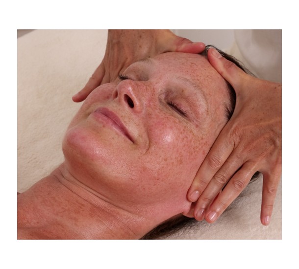 Mains de la praticienne enveloppant et massant les tempes et le cuir chevelu d'une femme allongée yeux fermés