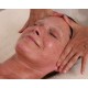 Mains de la praticienne enveloppant et massant les tempes et le cuir chevelu d'une femme allongée yeux fermés