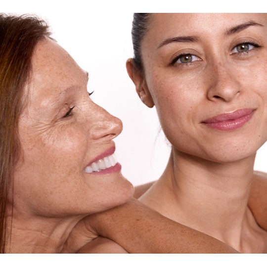 Deux femmes d'âges différents souriant côte à côte avec une peau lumineuse et sans maquillage