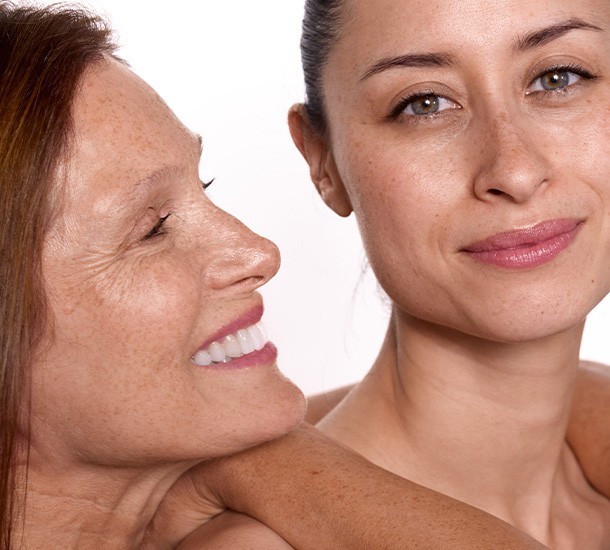 Deux femmes d'âges différents souriant côte à côte avec une peau lumineuse et sans maquillage